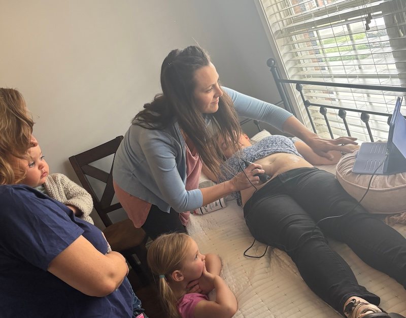 A midwife checking a pregnant client while family members watch