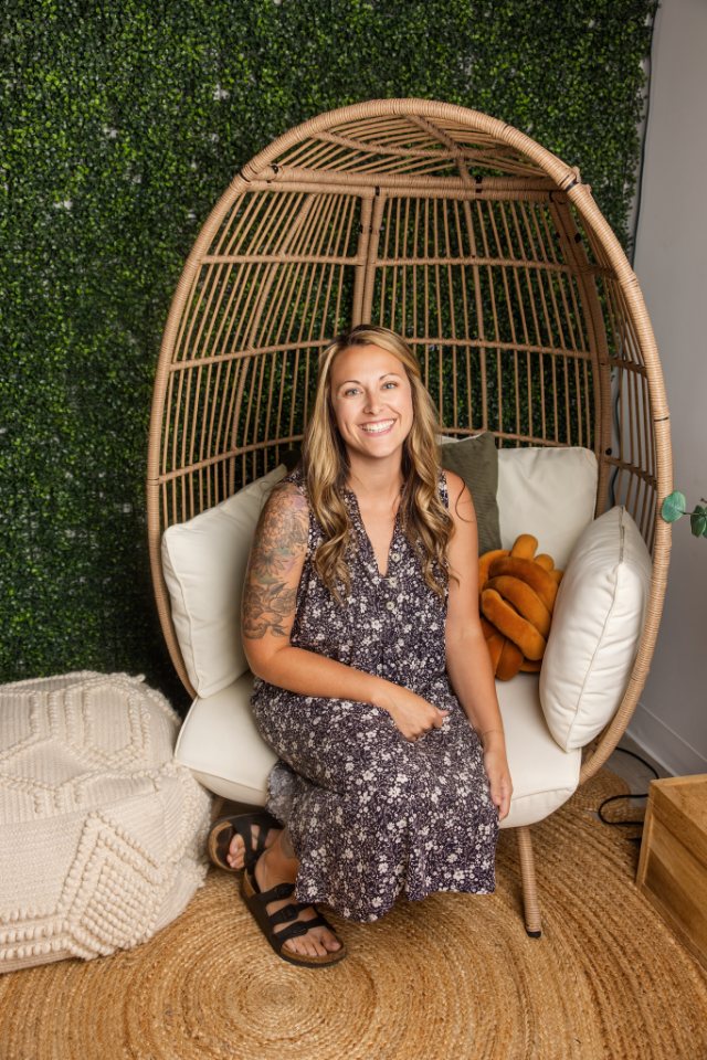 Kayla Searles, Certified Professional Midwife, seated in a wicker chair