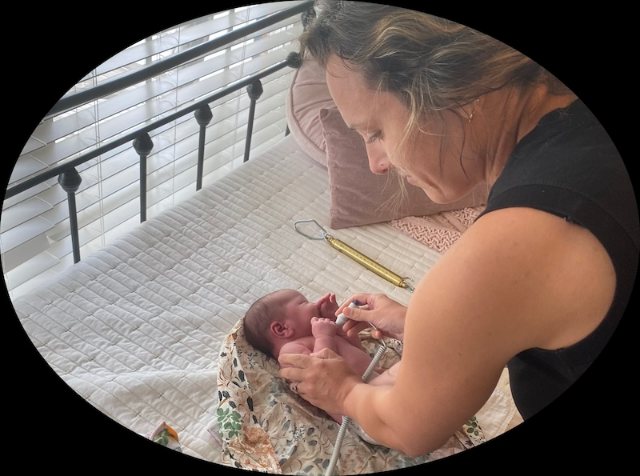 A midwife examining a newborn during a postpartum visit